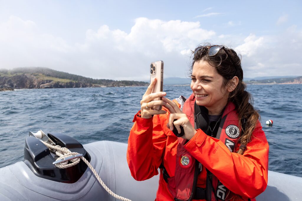 a guest takes a picture on a zodiac whale watching tour