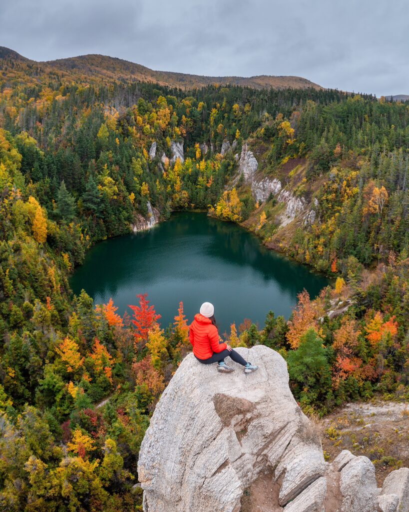 A hiker sits on a rock at the Gypsum Mine Lake on the Cabot Trail